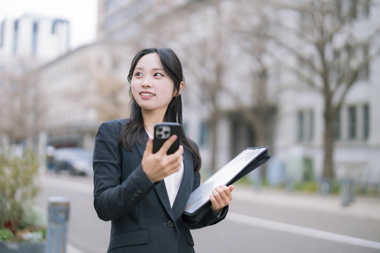 スマホを見ながら、資料確認する女性